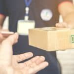 delivery man smiling and holding a cardboard box